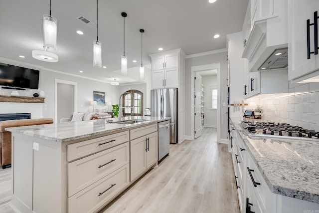 kitchen featuring a sink, appliances with stainless steel finishes, open floor plan, crown molding, and backsplash