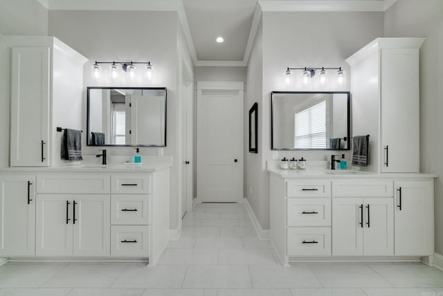 full bath featuring two vanities, baseboards, and crown molding