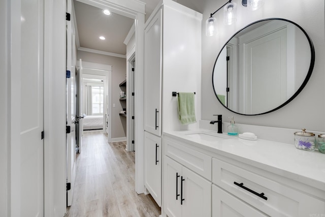bathroom with ornamental molding, wood finished floors, recessed lighting, vanity, and baseboards
