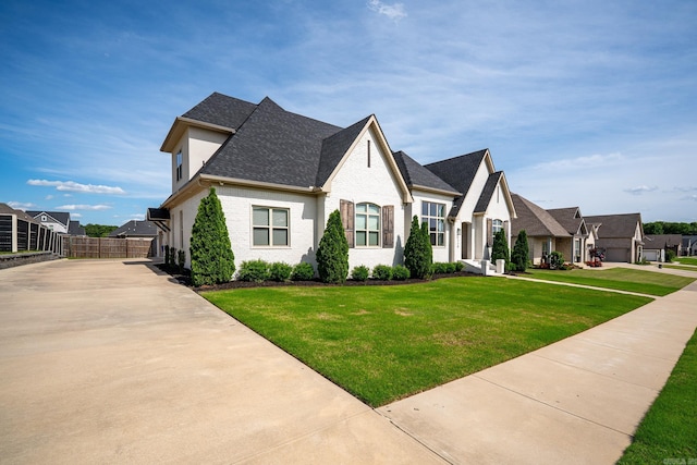 french country home with a shingled roof, a residential view, and brick siding