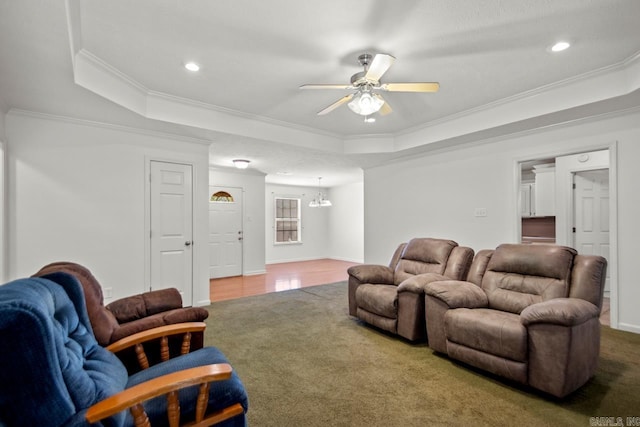 carpeted living area featuring a raised ceiling, ceiling fan, crown molding, recessed lighting, and a chandelier
