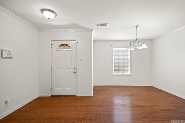 entryway with a chandelier, wood finished floors, crown molding, and baseboards