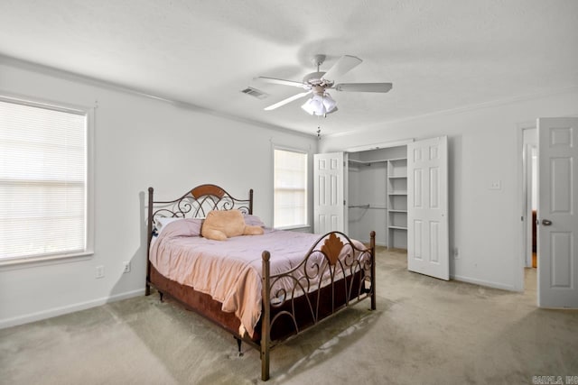 bedroom with light carpet, baseboards, a ceiling fan, a walk in closet, and a closet