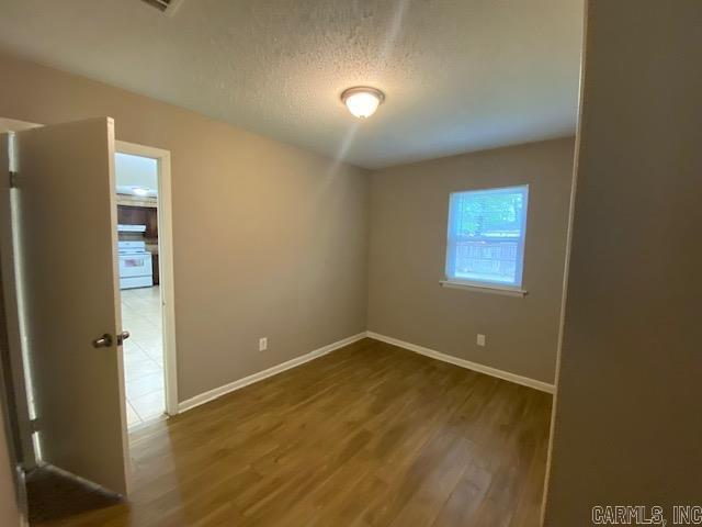 3804 Arapaho Trl, Little Rock, AR 72209 - unfurnished room with wood finished floors, baseboards, and a textured ceiling