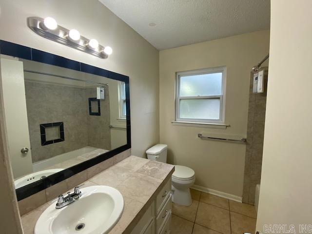 3804 Arapaho Trl, Little Rock, AR 72209 - full bath featuring tile patterned flooring, toilet, vanity, a shower, and a textured ceiling