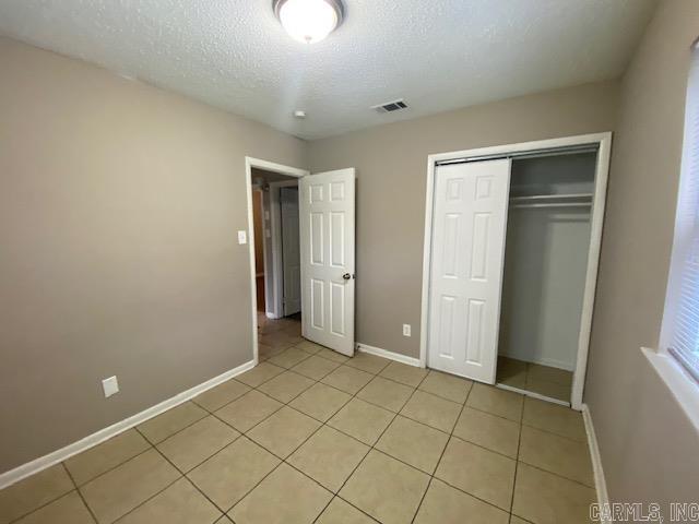 3804 Arapaho Trl, Little Rock, AR 72209 - unfurnished bedroom with a textured ceiling, light tile patterned floors, baseboards, and a closet