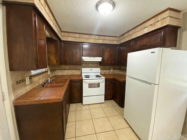 3804 Arapaho Trl, Little Rock, AR 72209 - kitchen with white appliances, under cabinet range hood, a sink, tasteful backsplash, and a textured ceiling