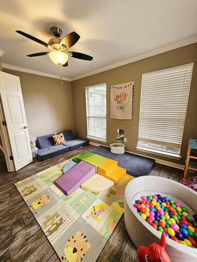 rec room featuring wood finished floors, ornamental molding, and a ceiling fan