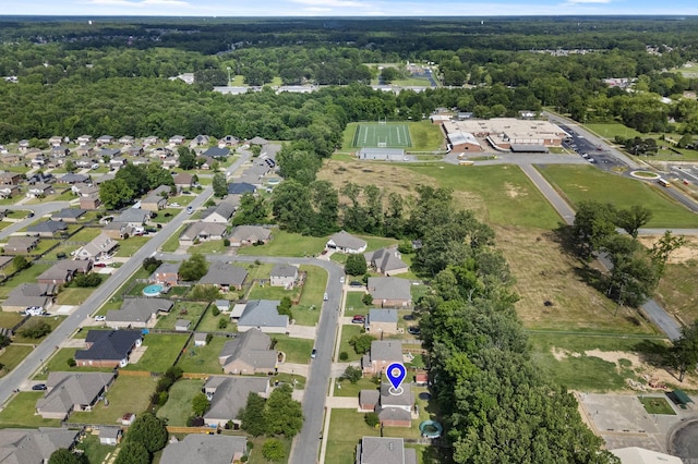 aerial view of property and surrounding area featuring a forest and nearby suburban area