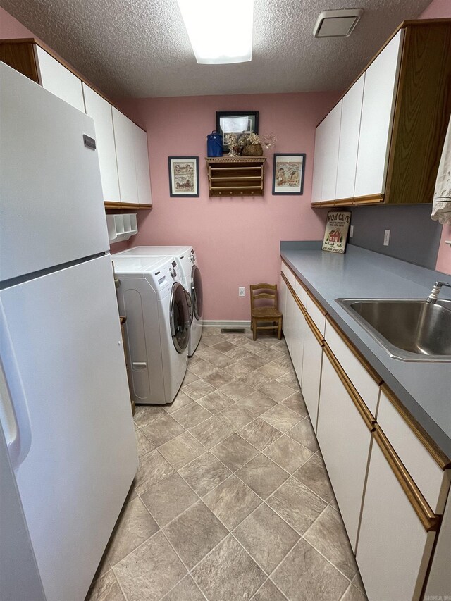 1502 Quail Creek Dr, Conway, AR 72032 - washroom with independent washer and dryer, cabinet space, a textured ceiling, and baseboards