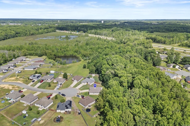 aerial view of property and surrounding area featuring a forest, a nearby body of water, and nearby suburban area