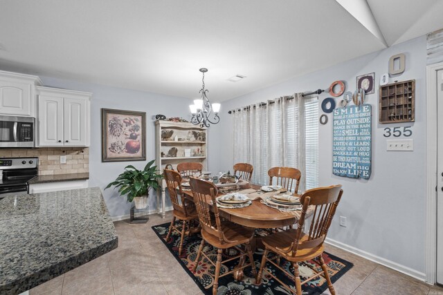 dining area with a chandelier, light tile patterned flooring, and baseboards