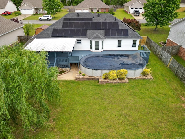 back of property featuring a shingled roof, a covered pool, a residential view, and roof mounted solar panels