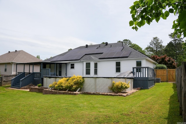 back of property featuring central AC unit, roof mounted solar panels, a deck, and a shingled roof
