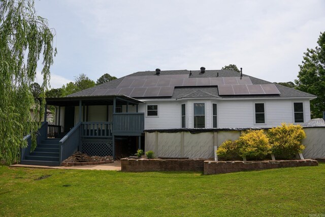 back of property with solar panels, a shingled roof, stairs, a lawn, and a covered pool