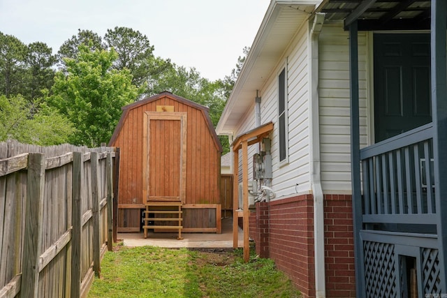 view of side of home featuring a storage unit, fence, brick siding, and an outdoor structure