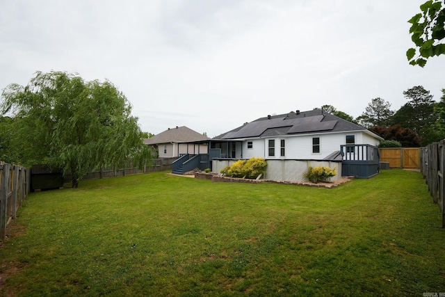 back of property featuring solar panels and a wooden deck