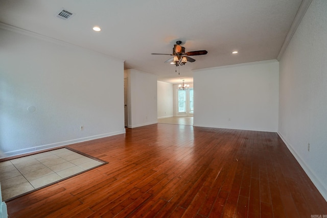 spare room with a chandelier, a ceiling fan, crown molding, hardwood / wood-style floors, and baseboards
