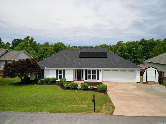 view of front of property with a shed, concrete driveway, roof mounted solar panels, a front yard, and a garage