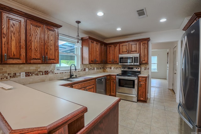 kitchen with appliances with stainless steel finishes, a sink, healthy amount of natural light, brown cabinetry, and crown molding