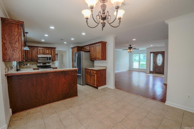 kitchen with stainless steel appliances, a chandelier, open floor plan, decorative backsplash, and a peninsula
