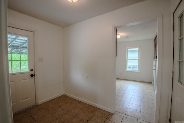 doorway to outside with light tile patterned floors and baseboards