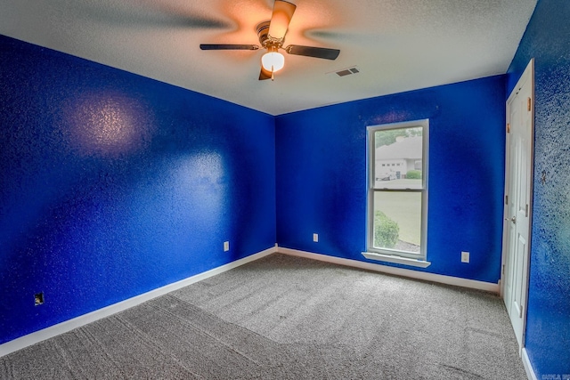carpeted empty room with ceiling fan, baseboards, and a textured ceiling