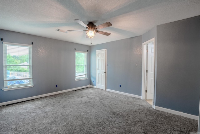 carpeted spare room featuring a ceiling fan, a textured ceiling, and baseboards