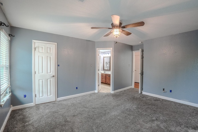 unfurnished bedroom featuring light carpet, baseboards, ensuite bath, and ceiling fan