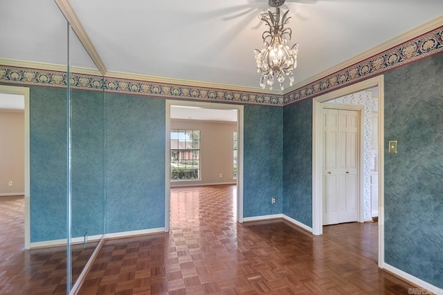 empty room with baseboards, a chandelier, crown molding, and wallpapered walls