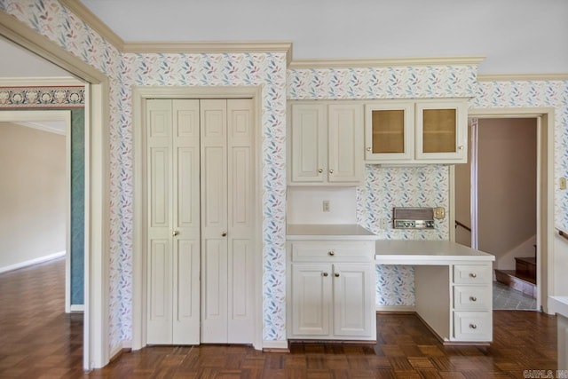 kitchen with ornamental molding, light countertops, glass insert cabinets, baseboards, and wallpapered walls