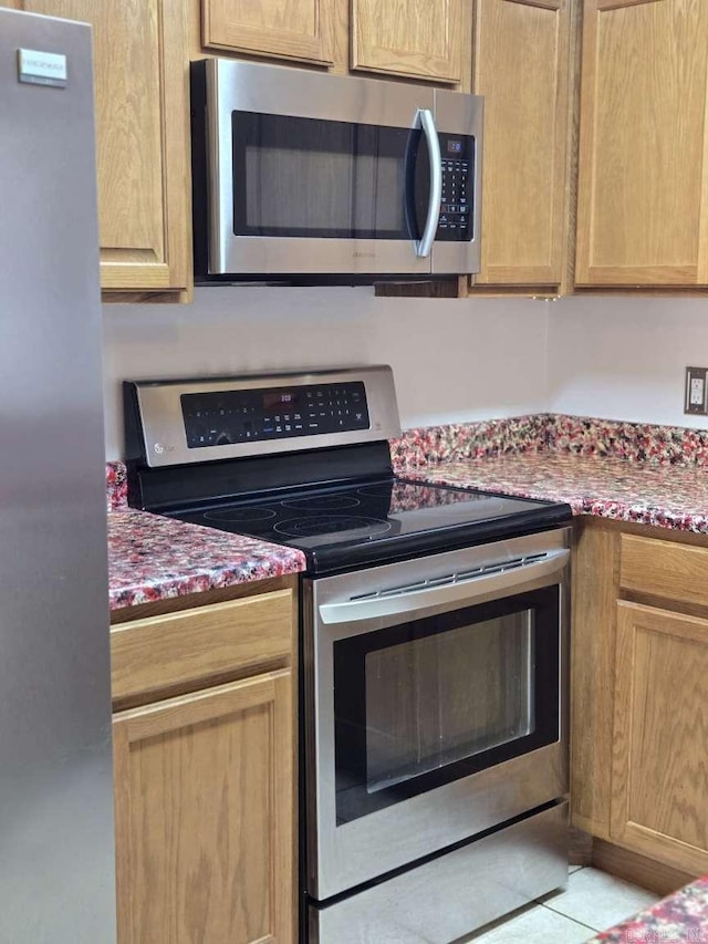 kitchen featuring appliances with stainless steel finishes, stone counters, and light brown cabinetry