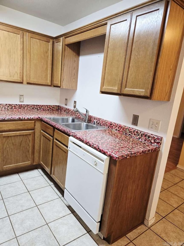 kitchen featuring dishwasher, a sink, light tile patterned floors, and dark countertops