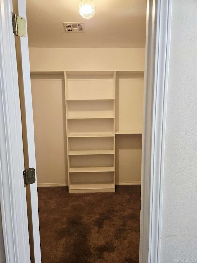 walk in closet with dark carpet