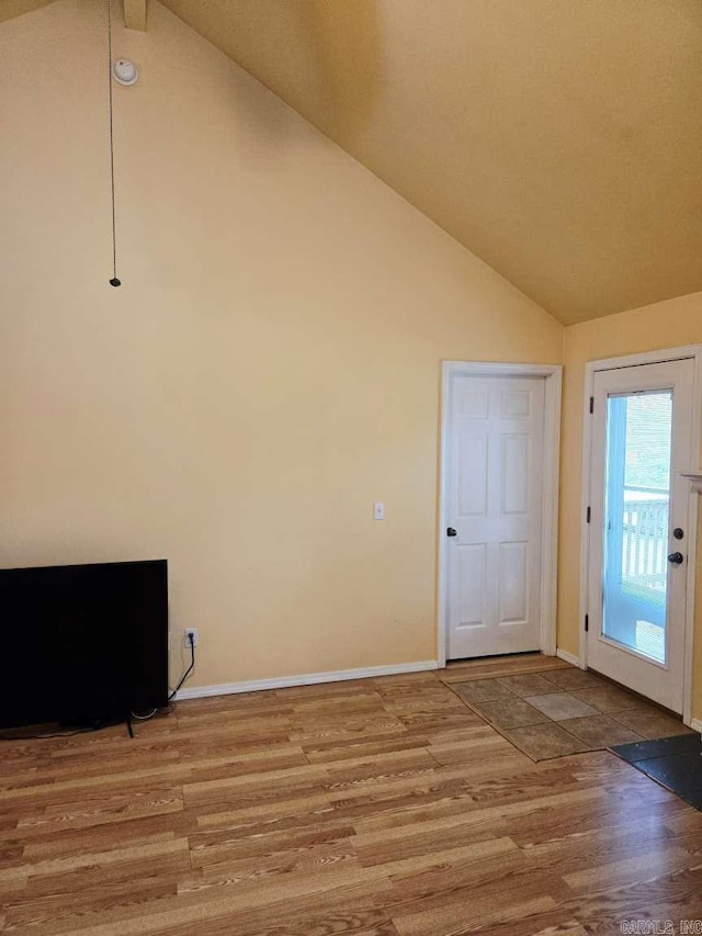 unfurnished room featuring vaulted ceiling, wood finished floors, and baseboards