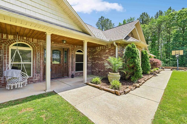 402 Demuth, Benton, AR 72019 - property entrance featuring brick siding, roof with shingles, covered porch, and a yard