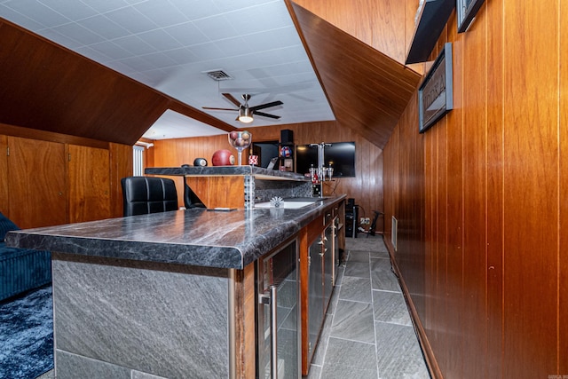1705 W Cedar St, El Dorado, AR 71730 - kitchen featuring wooden walls, wine cooler, a ceiling fan, dark countertops, and brown cabinets