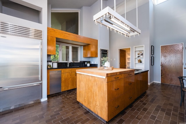 1 Rivers Edge Dr, Little Rock, AR 72227 - kitchen featuring a high ceiling, stainless steel appliances, brick patterned flooring, baseboards, and a center island