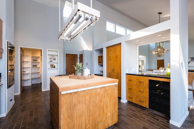 1 Rivers Edge Dr, Little Rock, AR 72227 - kitchen featuring butcher block countertops, a high ceiling, a chandelier, brick flooring, and brown cabinetry
