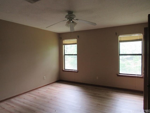 unfurnished room featuring a ceiling fan, light wood-style flooring, and baseboards