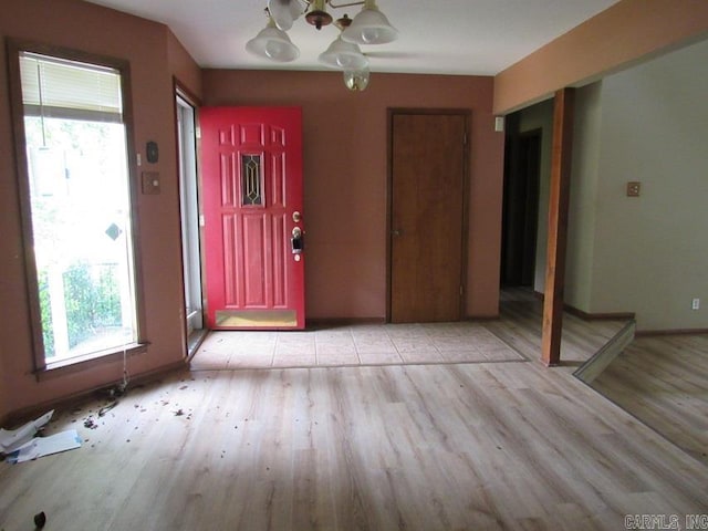 foyer entrance featuring a chandelier, light wood finished floors, and baseboards