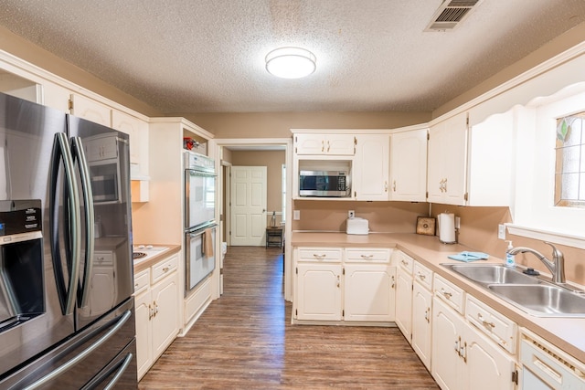 204 Riverside Dr, Pangburn, AR 72121 - kitchen with appliances with stainless steel finishes, a sink, a textured ceiling, light wood-style floors, and white cabinetry