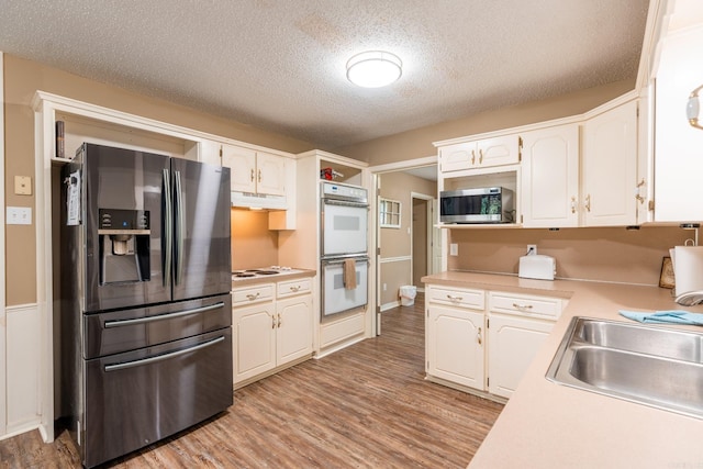204 Riverside Dr, Pangburn, AR 72121 - kitchen with appliances with stainless steel finishes, light countertops, under cabinet range hood, light wood-style floors, and white cabinetry