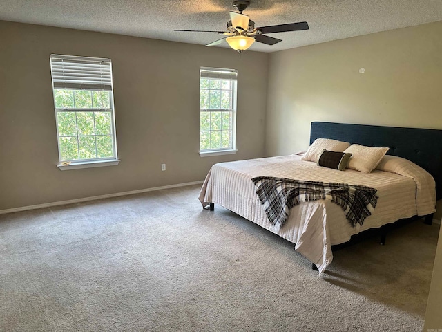 bedroom with a textured ceiling, carpet floors, baseboards, and a ceiling fan