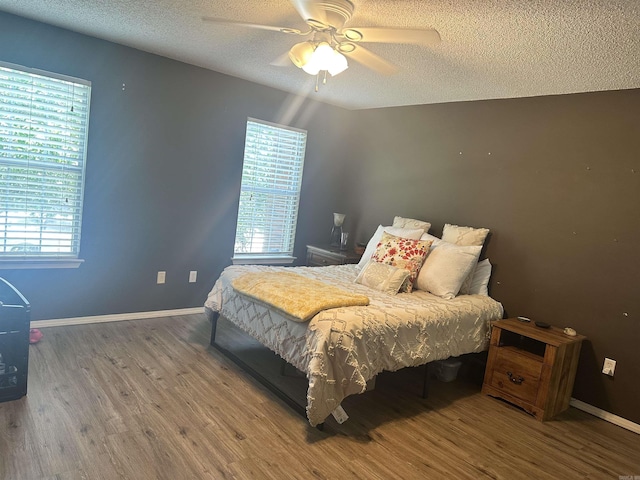 bedroom featuring wood finished floors, a textured ceiling, baseboards, and ceiling fan