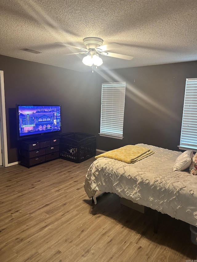 bedroom featuring wood finished floors, a textured ceiling, and ceiling fan
