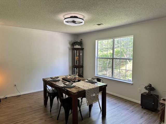 dining area with a textured ceiling, dark wood-type flooring, baseboards, and crown molding