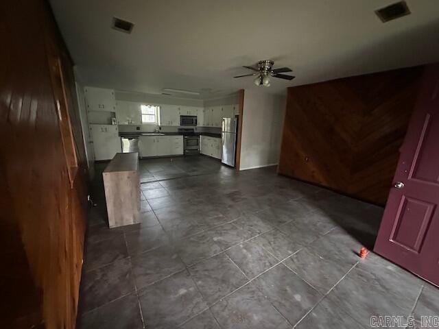 unfurnished living room with ceiling fan, dark tile patterned flooring, and a sink