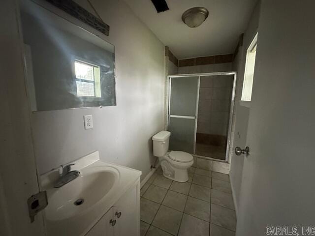 bathroom featuring tile patterned flooring, a stall shower, toilet, vanity, and baseboards
