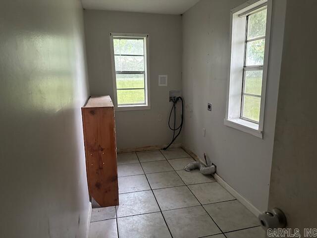 clothes washing area featuring electric dryer hookup, hookup for a washing machine, light tile patterned floors, and baseboards